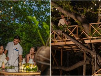 Three adults at an outdoor candlelit garden dinner, smiling and conversing around a table with candles and greenery in a lush setting.